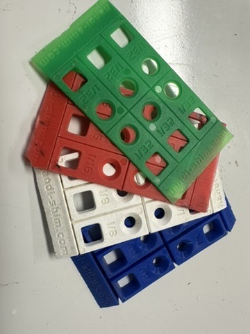 Red, green, blue, and white Handi-Shim plastic construction shims arranged on a workbench.