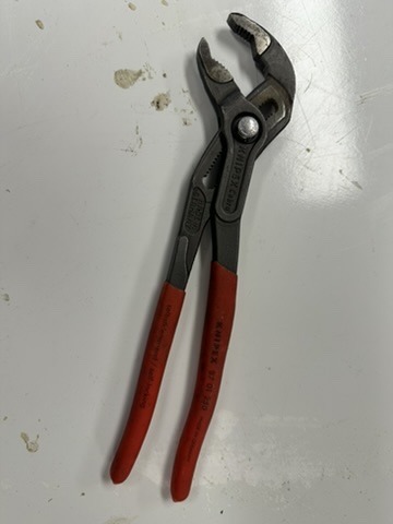 A well-used pair of larger Knipex Cobra water-pump pliers on a workbench.