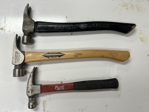 Three used hammers laid side by side: a Dead On framing hammer, a Stiletto titanium hammer, and a Plumb smooth-face hammer.